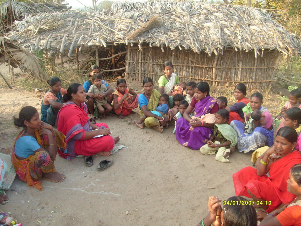 Women gathering in a makeshift Adivasi village