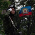 Soldat vor der Flagge der Volksrepublik Lugansk (LNR)